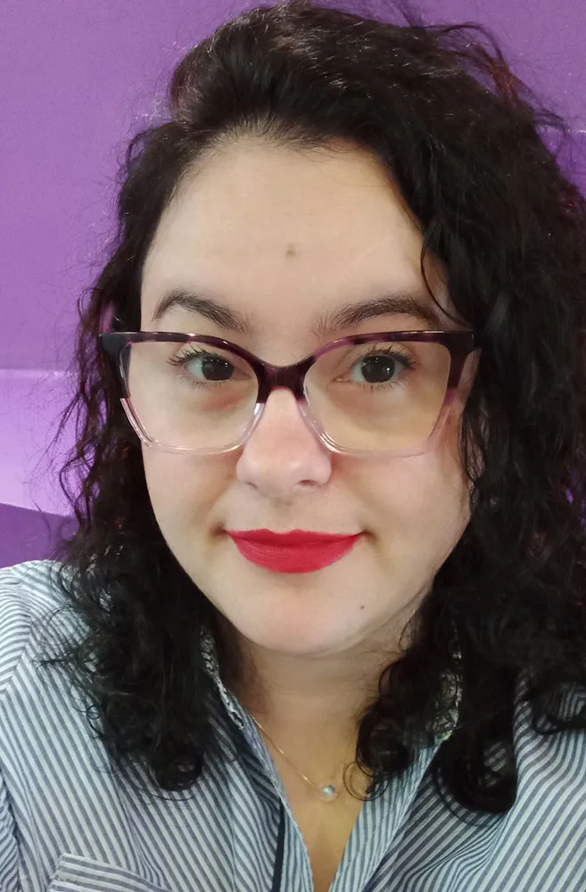 Picture of Camila Pires, a white woman with a round face, red lipstick and purple glasses.