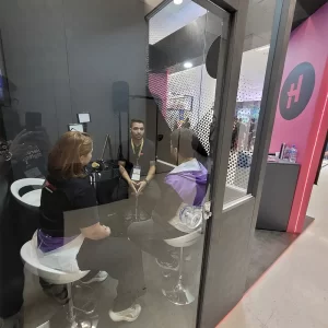 A photo of a interview cabin with three people talking inside of it.