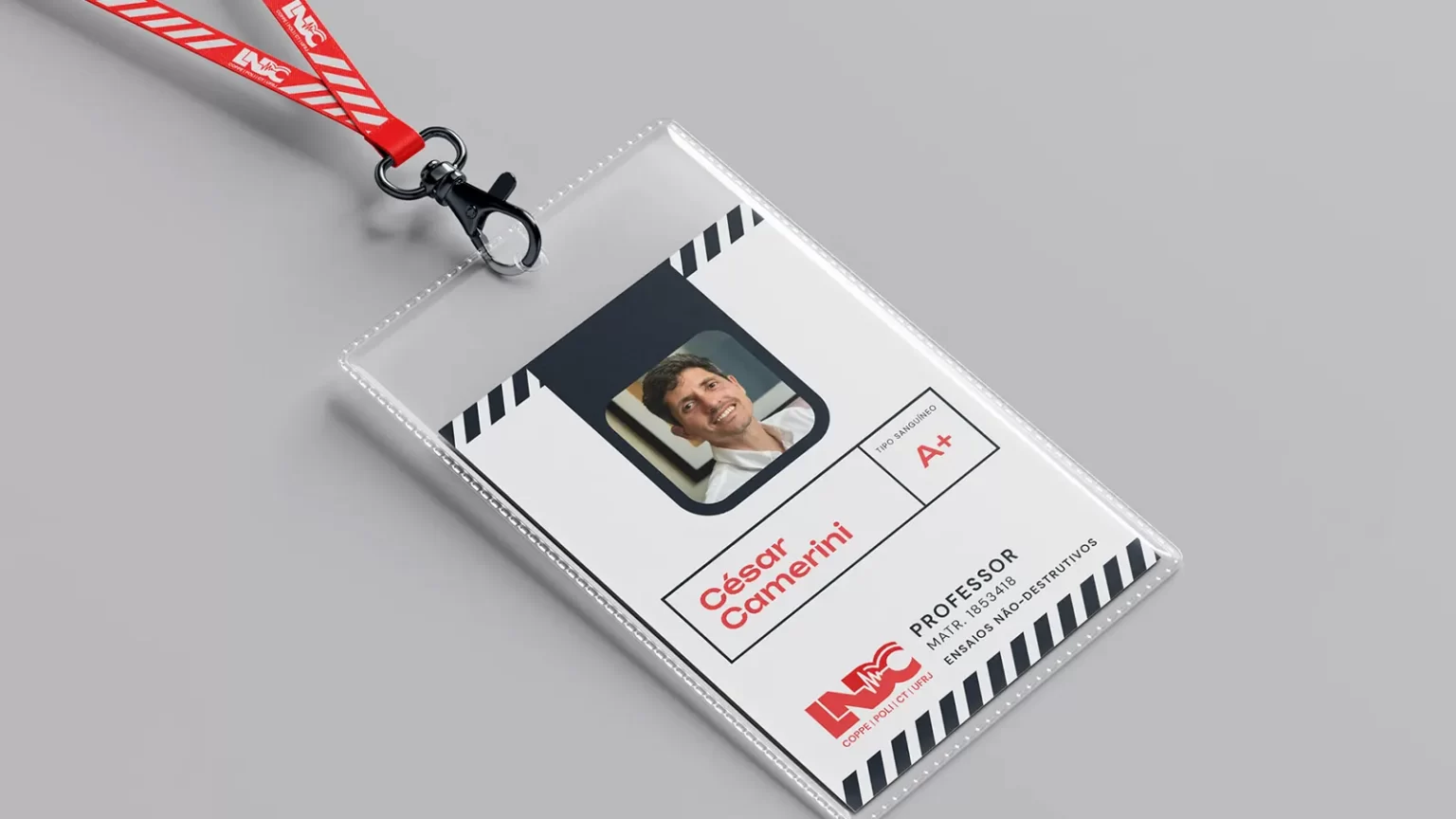 LNDC new ID tag mockup, off-white, with navy bars and red main text. It portraits one of the professors, a smiling mature man in a white shirt.